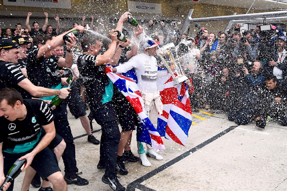 Tradition muss sein: Hamilton (in weiß) und sein Team feiernden Titel 2015 mit Champagner