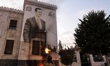 A Syrian opposition fighter shoots at an image of ousted Syrian President Bashar al-Assad in the Syrian city of Hama on Thursday. 