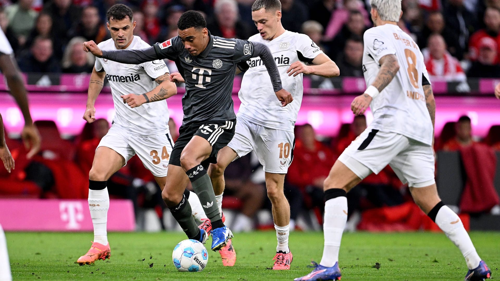 Jamal Musiala (center) in a duel with several Leverkusen players: The game against the champions takes place on a Saturday evening.