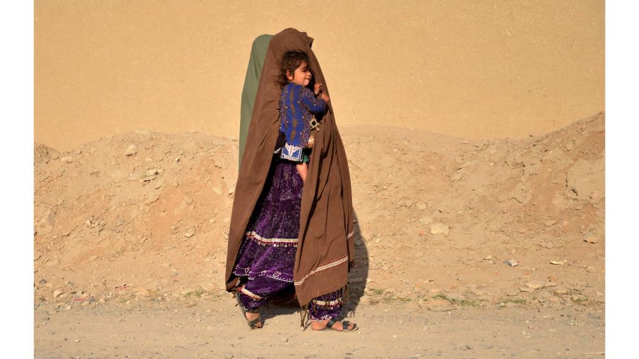 Photogallery A woman with a child walks on the shoulder of a road in the Zhari district, Kandahar province, Afghanistan