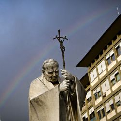 An rainbow appears on a statue of Pope John Paul II abroad of the Gemelli Hospital, where Pope Francis is admitted to testing and receiving treatment for bronchitis in Rome. | Photo: Tiziana Fabi / AFP