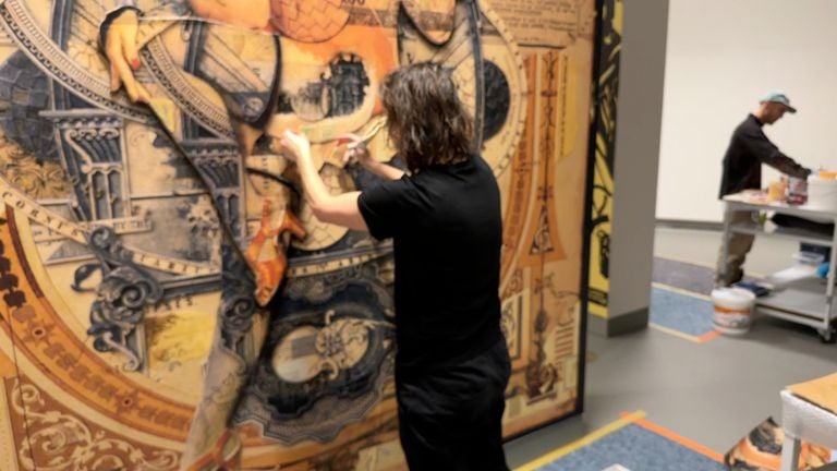 Artist Handiedan works with paper and glue for her Mural.
