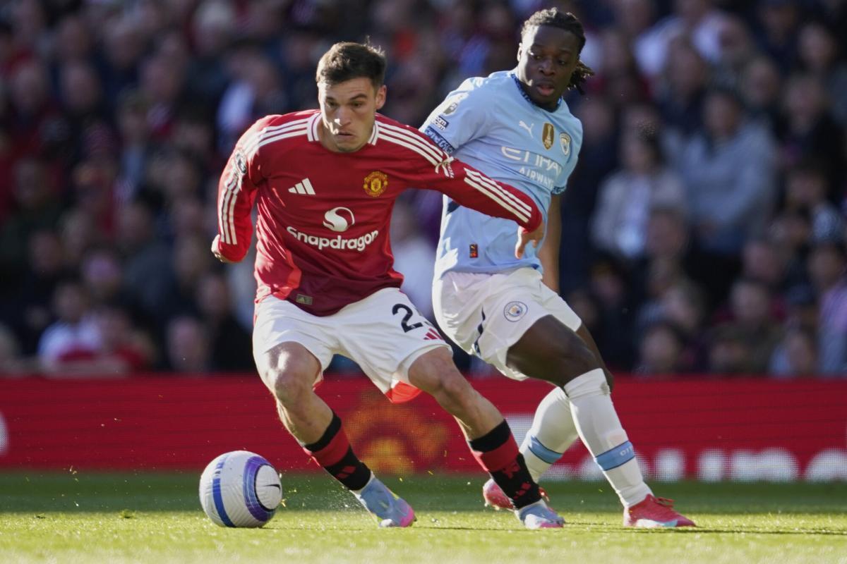 Manchester United's Manuel Ugarte, left, and Manchester City's Jeremy Doku fight for the ball during the English Premier League soccer match between Manchester City and Manchester United in Manchester, England, Sunday, April 6, 2025. (AP Photo/Dave Thompson)