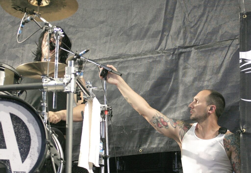 Roadie aligns the microphone of a drummer exactly