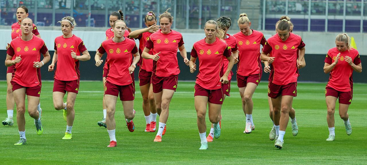 The German players run on the lawn in a stadium.
