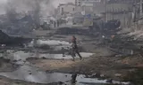 Palestinian girl runs past destroyed buildings in Gaza city.