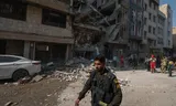 An Iranian police officer runs past a residential building that was destroyed on Friday by the Israeli attacks on Tehran. Photo Morteza Nikoubazl/Nurphoto via Getty Images 