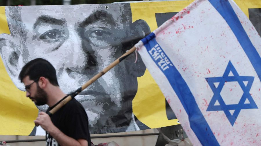 Photo gallery A protester with the Israeli flag passes by a portrait of Prime Minister Benjamin Netanyahu during an anti -government protest that demands the release of captive Israeli hostages