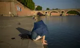 A man uses an umbrella against the sun on the Garonne River in Toulouse, France.