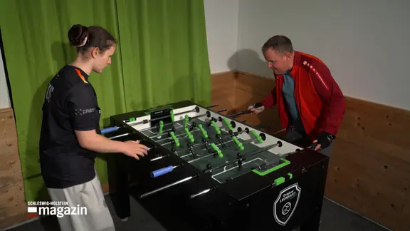 Two people play table football.