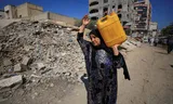 A Palestinian woman with a jerry can water.