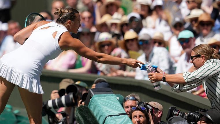 Help from tennis superstar: Aryna Sabalenka extends a water bottle to the audience.