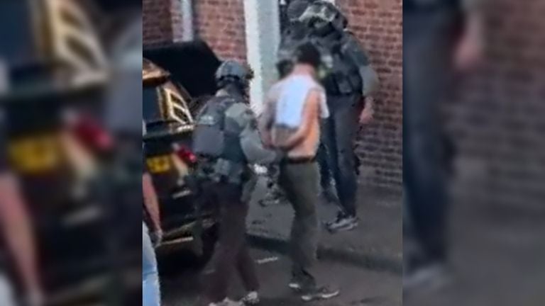 The man is taken out of the house by the arrest team.