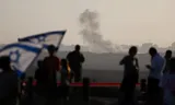 Israelis who want Gaza to come into the hands of Israel for good, see smoke rising in the Gaza Strip last Wednesday from a vantage point on the border. Photo Ronen Zvulun/Reuters 