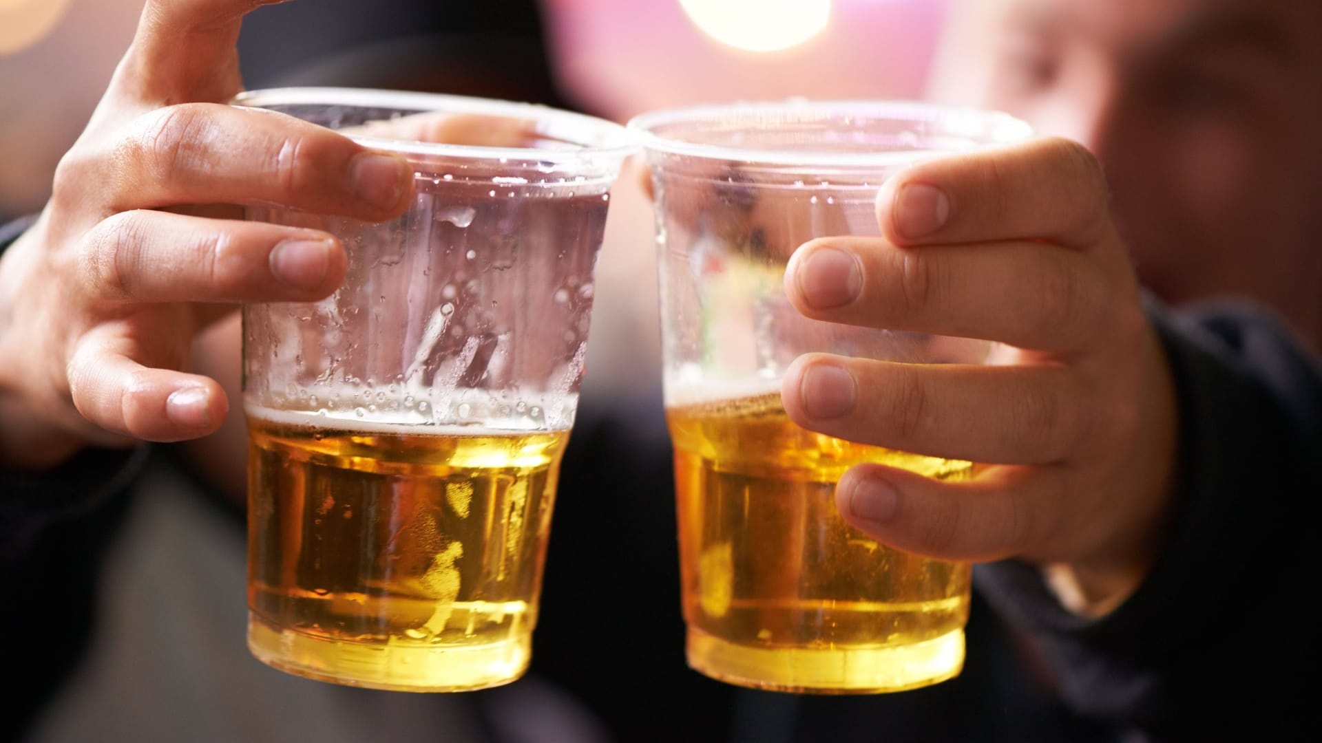 A man holds two plastic cups filled with beer (symbol image): Eintracht Braunschweig attracts the prices in the stadium.