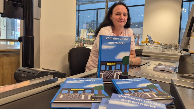 Monique with her book behind the checkout of the supermarket (photo: Niek de Bruijn).