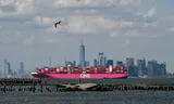 A container chip from Ocean Network Express (One) sails along the Manhattan skyline while it is leaving the port of New York.