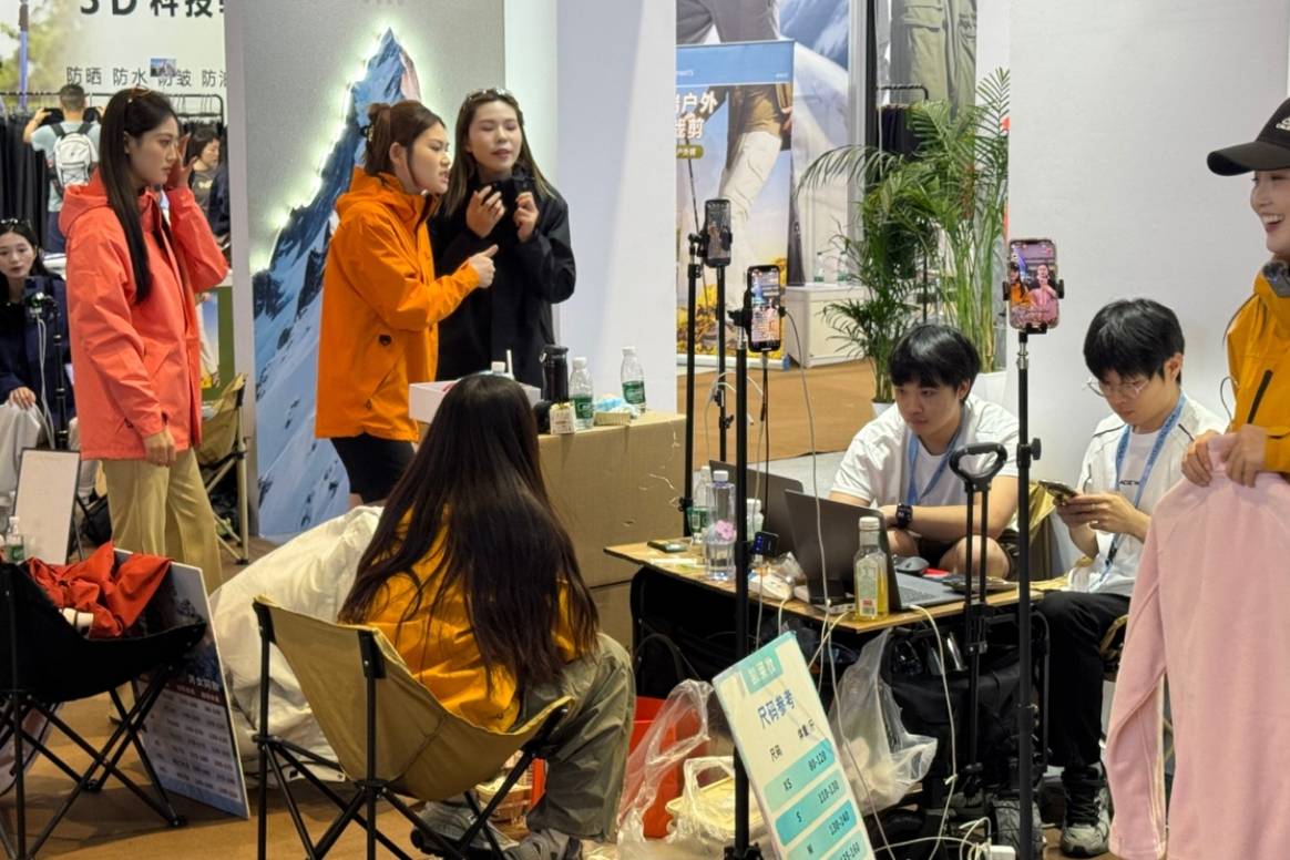 Employees of an outwear brand present jackets in the social media livestream at the booth