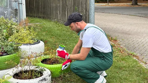The new VfL-Wolfsburg player Christian Eriksen paints a car tire with color.