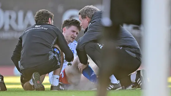 Noah Katterbach (M.) from Hamburger SV is injured on the ground and is treated
