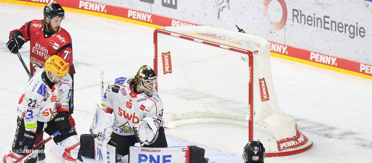 Ice hockey players of the Fischtown Penguins from Bremerhaven defend their goal against the Cologne Haie, goalkeeper Kristers Gudlevskis looks behind him for the puck, who slipped past his goal.