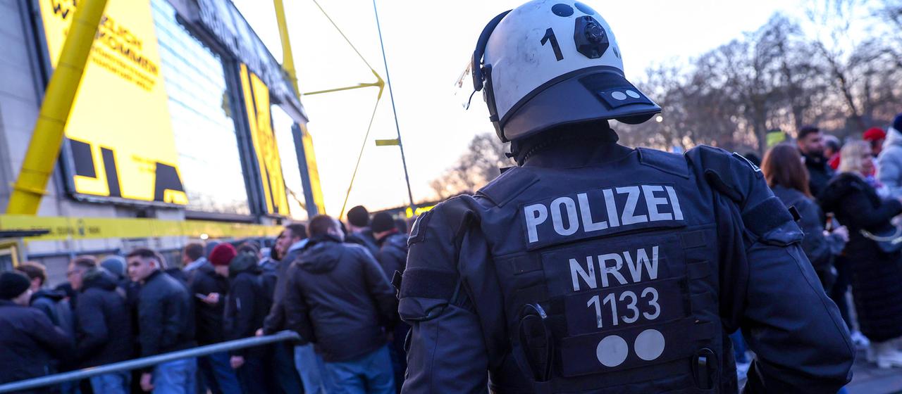 A police officer observes fans entering Dortmund.