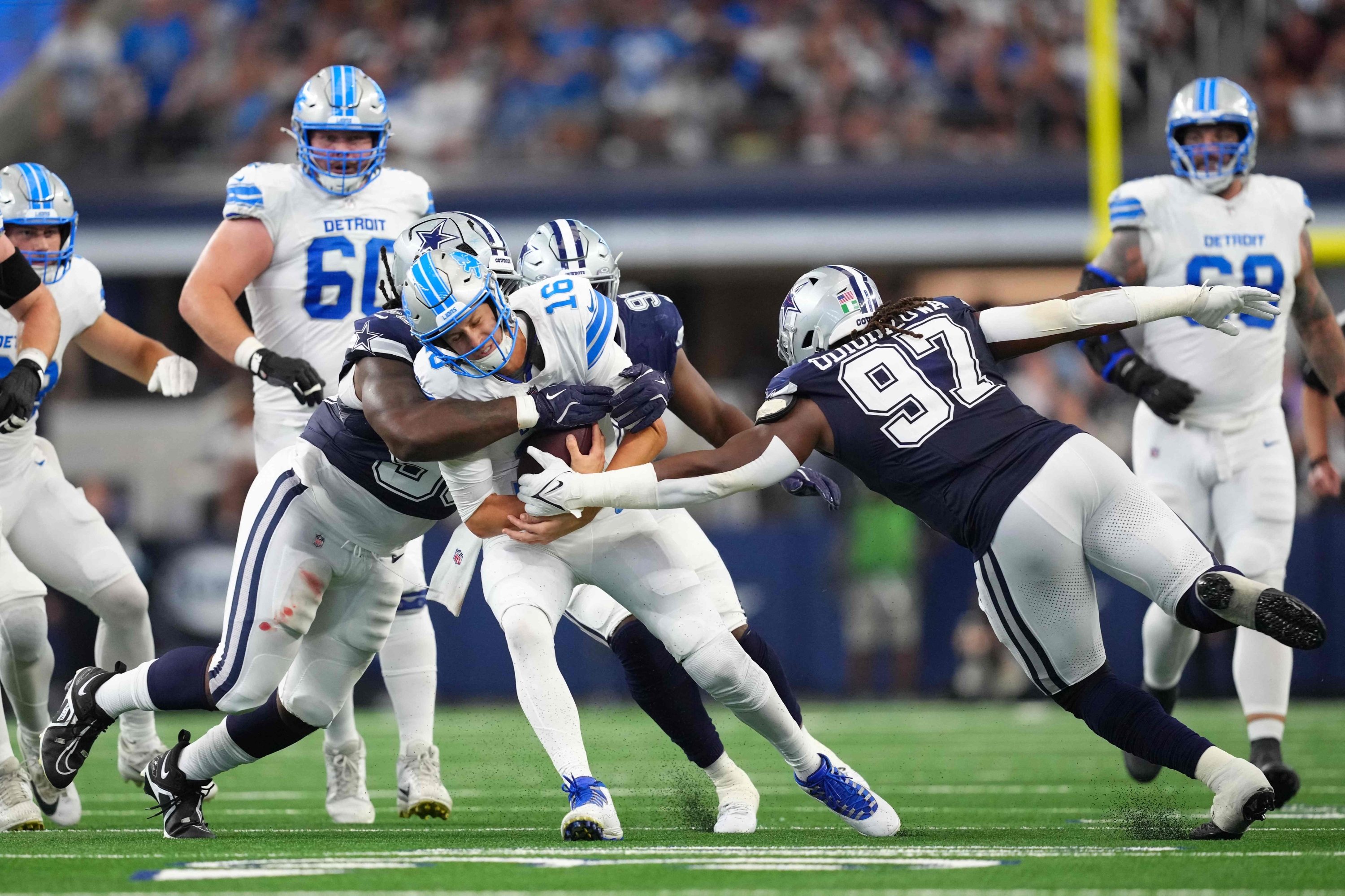 ARLINGTON, TEXAS - OCTOBER 13: Jared Goff #16 of the Detroit Lions is sacked by Mazi Smith #58 and Osa Odighizuwa #97 of the Dallas Cowboys in the second quarter of a game at AT&T Stadium on October 13, 2024 in Arlington, Texas. Sam Hodde/Getty Images/AFP (Photo by Sam Hodde / GETTY IMAGES NORTH AMERICA / Getty Images via AFP)