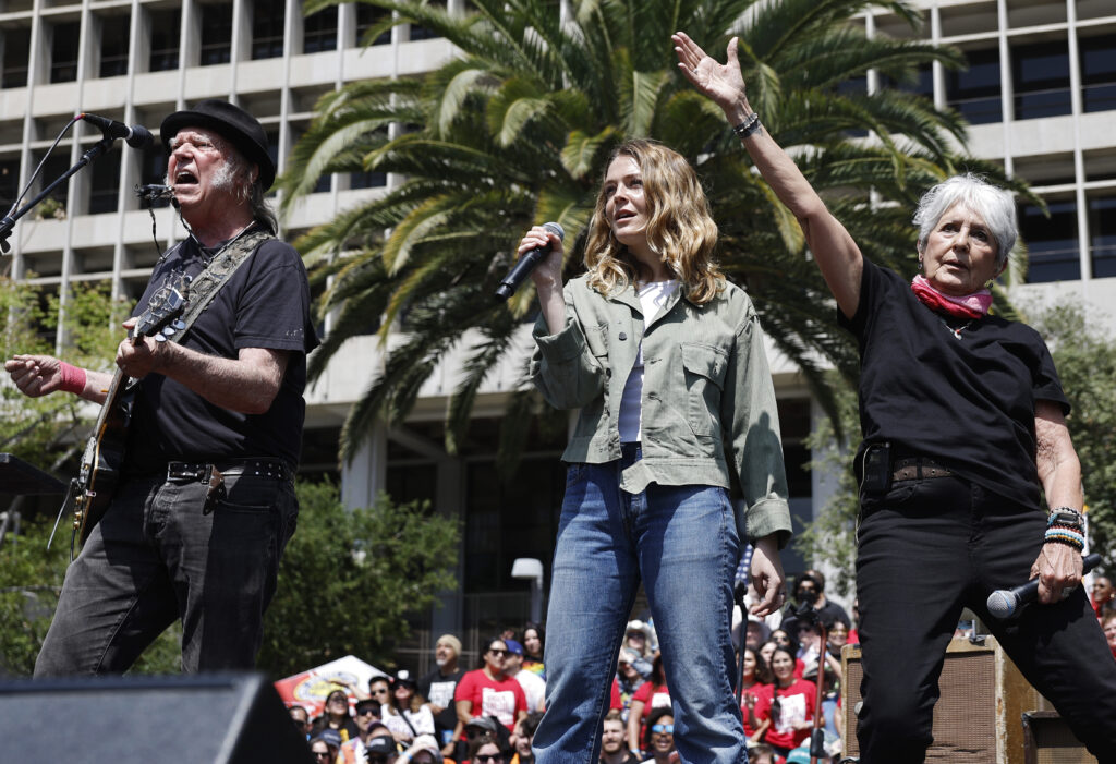LOS ANGELES, CALIFORNIA - APRIL 12: (L to R) Neil Young, Maggie Rogers and Joan Baez perform during the 'Fighting Oligar...
