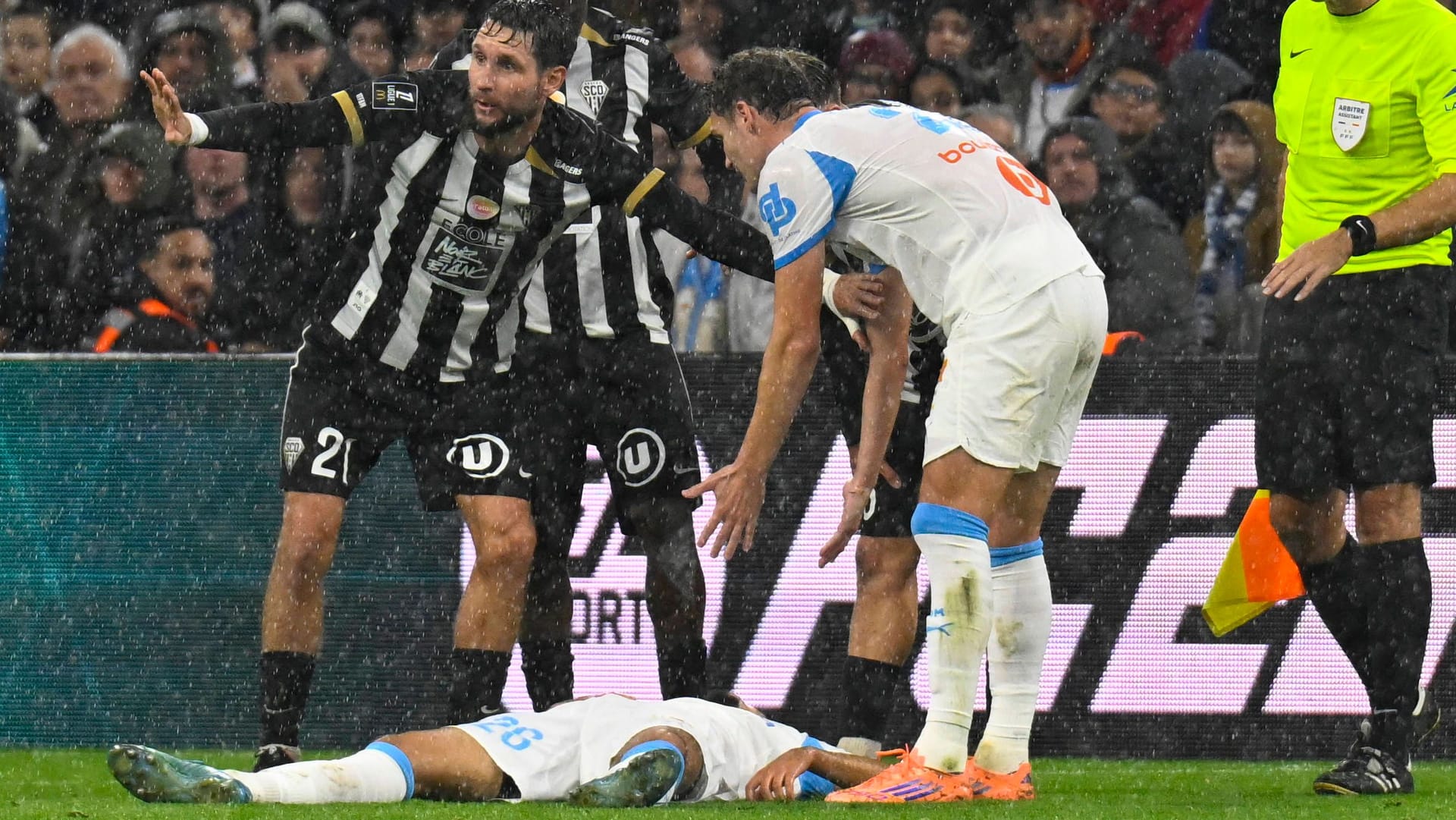 Bilal Nadir (below) is lying on the ground, teammates and opponents rush to help: The young footballer collapsed on Wednesday.