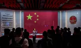 A guide addresses visitors in front of the Chinese national flag and emblem at the National Security Exhibition Gallery, ahead of the fifth anniversary of the National Security Law in Hong Kong, China, on June 20, 2025.