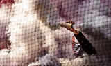 A masked Feyenoord fan sets off a smoke bomb from behind the net in De Kuip, during the championship match against Go Ahead Eagles on May 14, 2023. Photo Pim Ras/ANP 