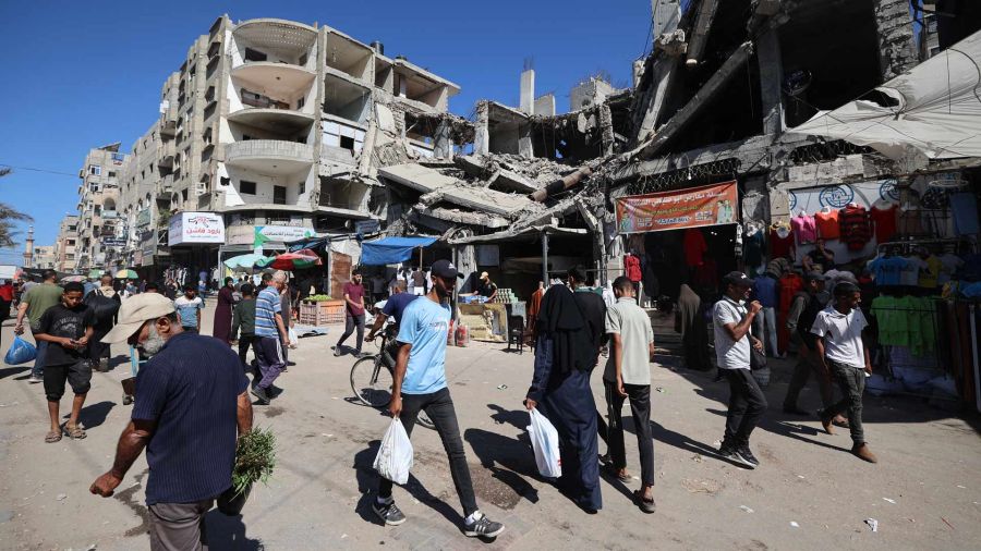 Photogallery Palestinians walk next to a destroyed building in a makeshift market in the Nuseirat refugee camp, located in the center of the Gaza Strip, three days after the ceasefire came into force