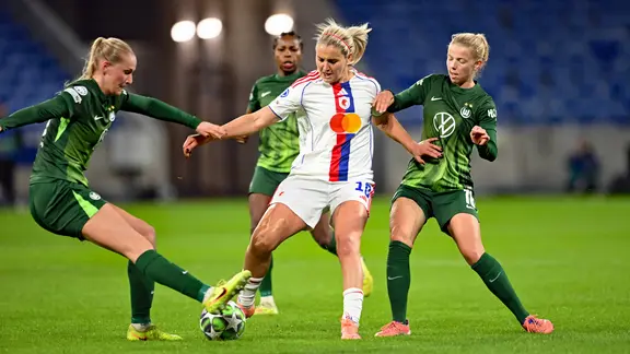 The Wolfsburg women try to steal the ball from Lyon's Lindsey Heaps