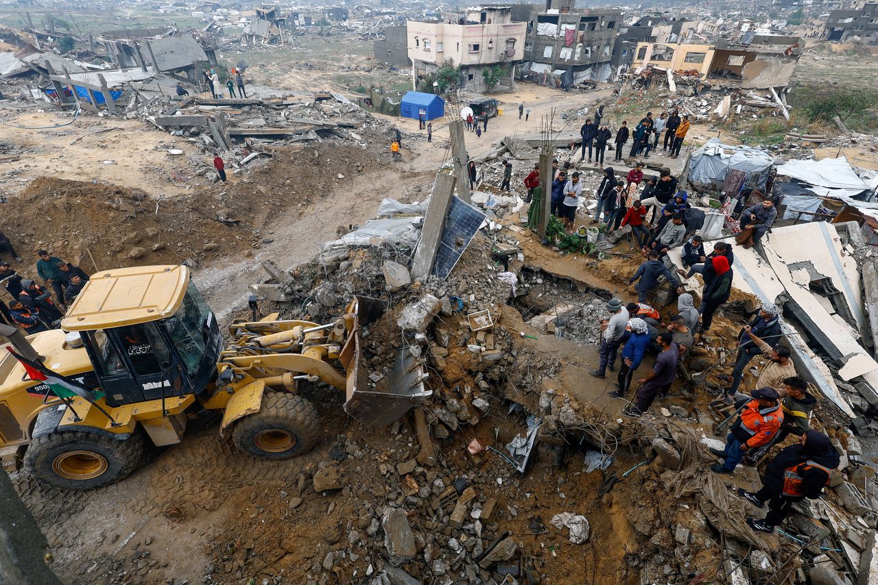 Bulldozers dig through the rubble of a collapsed house looking for bodies. 