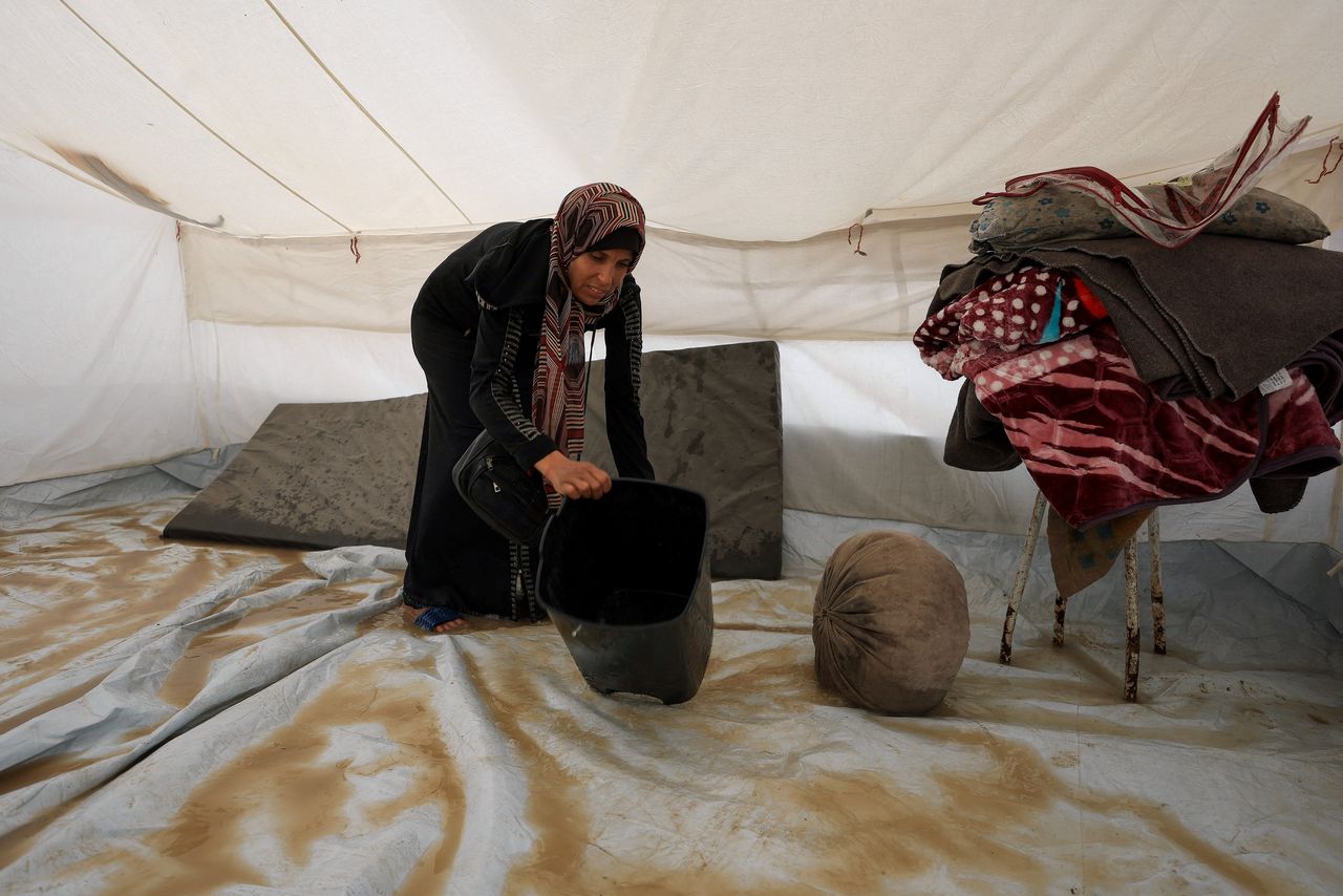Palestinians try to dry their sleeping areas with buckets. 