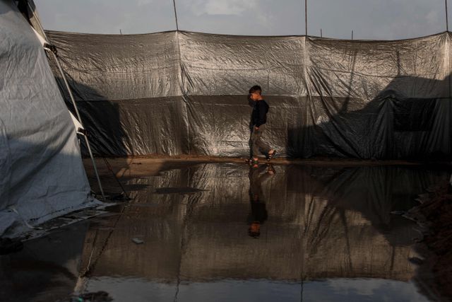 A boy walks through a flooded alley in a makeshift camp for displaced Palestinians in Gaza City's Zeitoun neighborhood. 