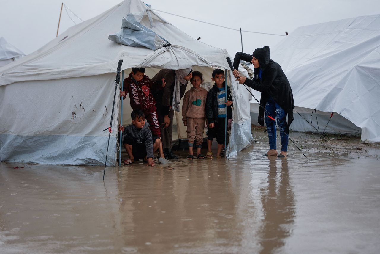 A woman repairs her tent while the children wait. 