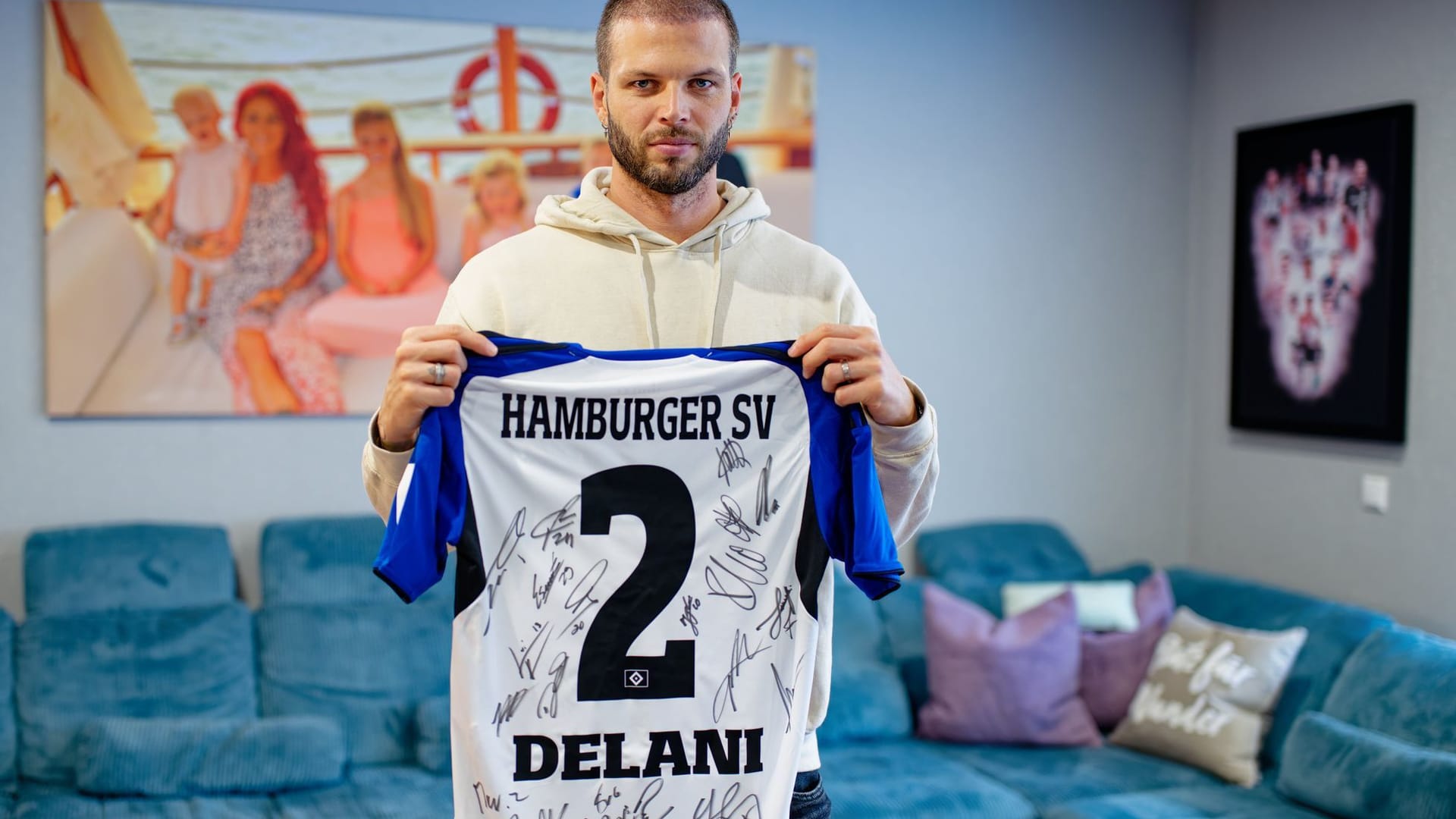 In his apartment, former soccer player Dennis Diekmeier holds a Hamburger SV jersey with the name of his eldest daughter Delani in his hands.