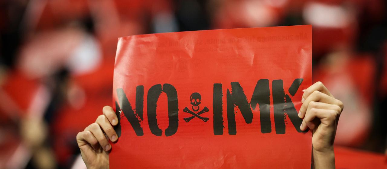 Fan holds a placard with the inscription "No IMK" upwards