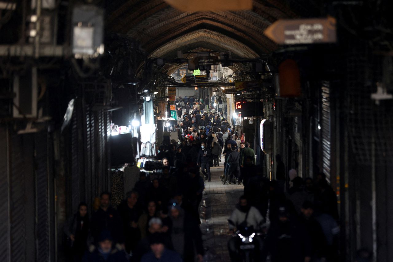 Iranians walk past closed shops at a central bazaar in Tehran.  
