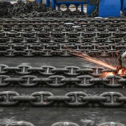 Employees make anchor chains at the production line of Zhongyun Marine Equipment in Suqian, east China's Jiangsu Province. | Photo: STR / AFP