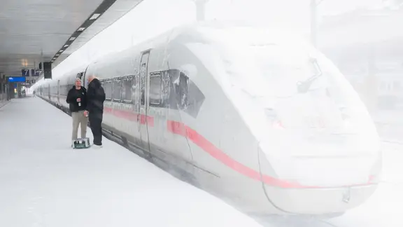 Two HSV fans stand with a crate of beer in front of a Deutsche Bahn ICE train in Hanover. 