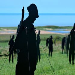 This photograph shows wooden silhouettes of British soldiers installed as part of the installation "standing with giants" at the British Normandy World War II Memorial. | Photo: Damien Meyer / AFP
