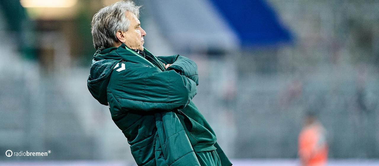 Werder's soccer coach Horst Steffen stands on the sidelines during a game with his arms crossed and leans back very far.