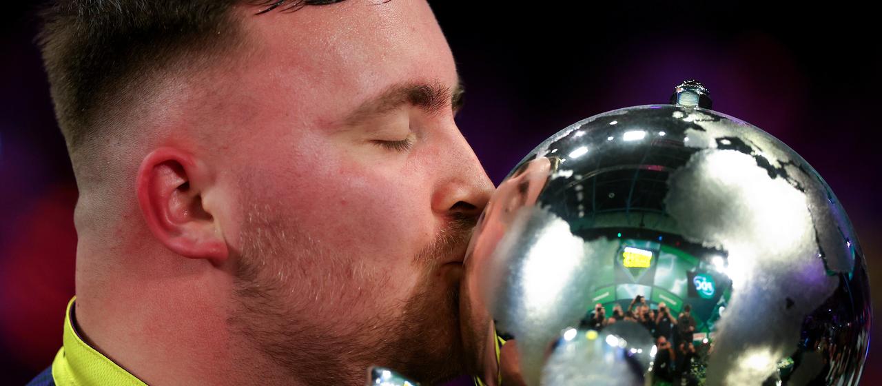 Luke Littler kisses the World Cup trophy
