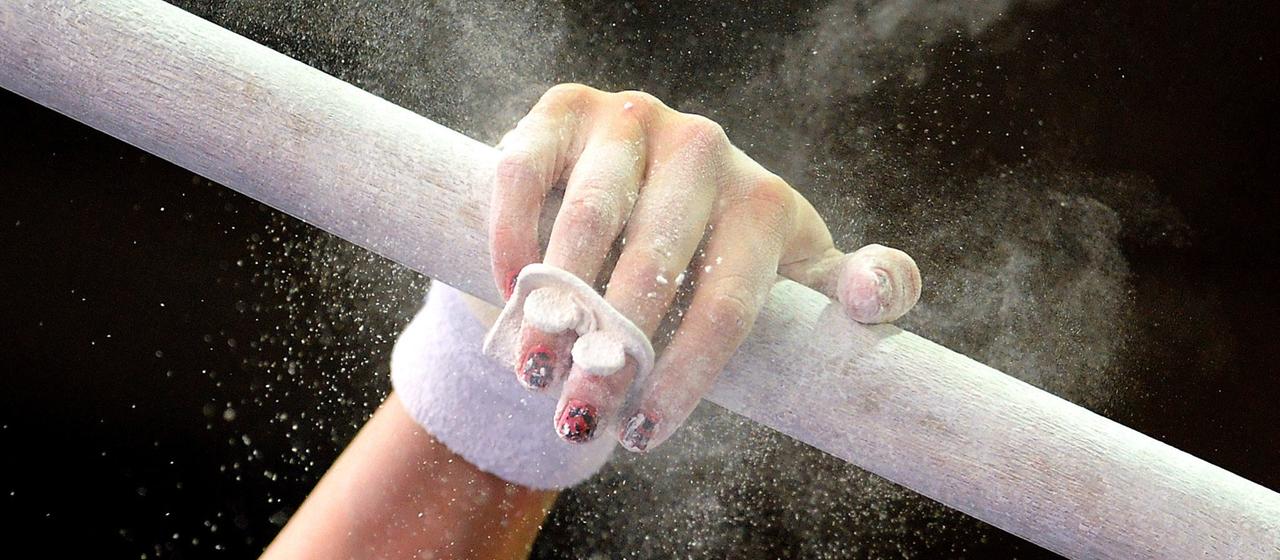 A gymnast's hand reaches for the bar