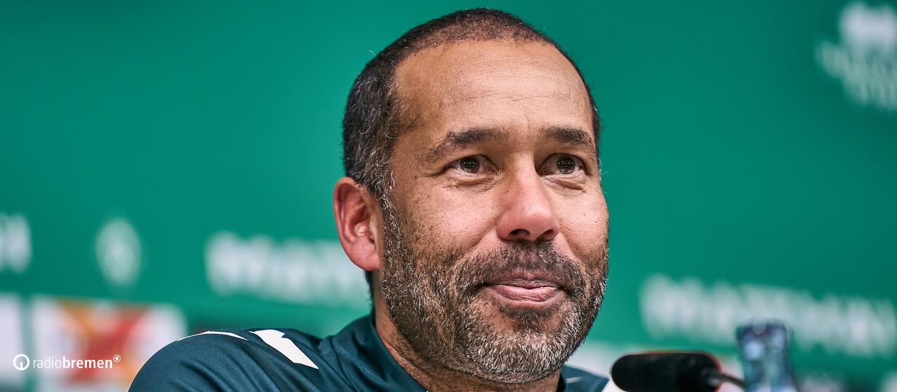 Werder's new soccer coach Daniel Thioune sits smiling on the podium at his first press conference.