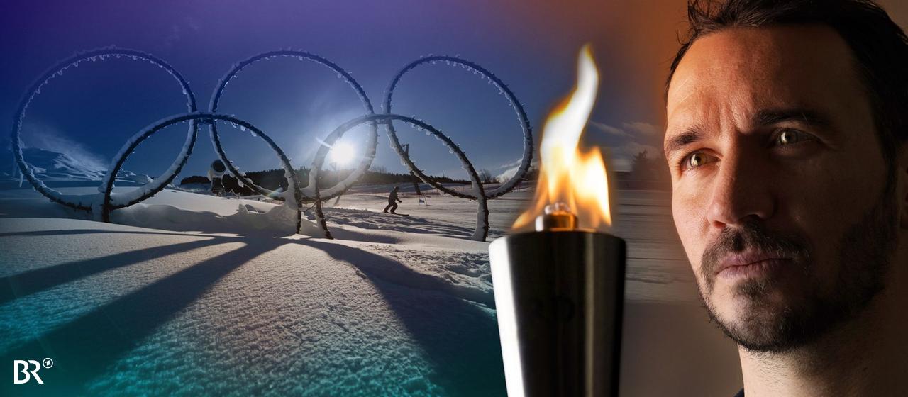 Felix Neureuther looks thoughtfully at an Olympic torch in his hand, in the background the Olympic rings standing in the snow at the Stelvio Ski Center in Bormio. 