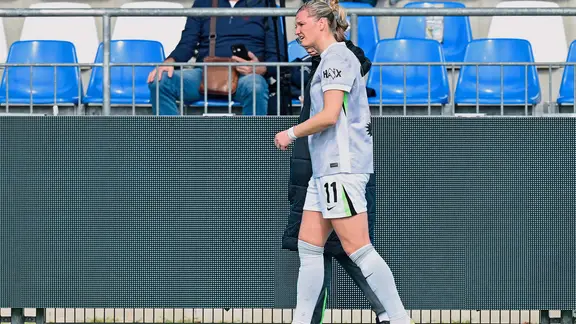 Alexandra Popp walks with a supervisor in front of a grandstand.