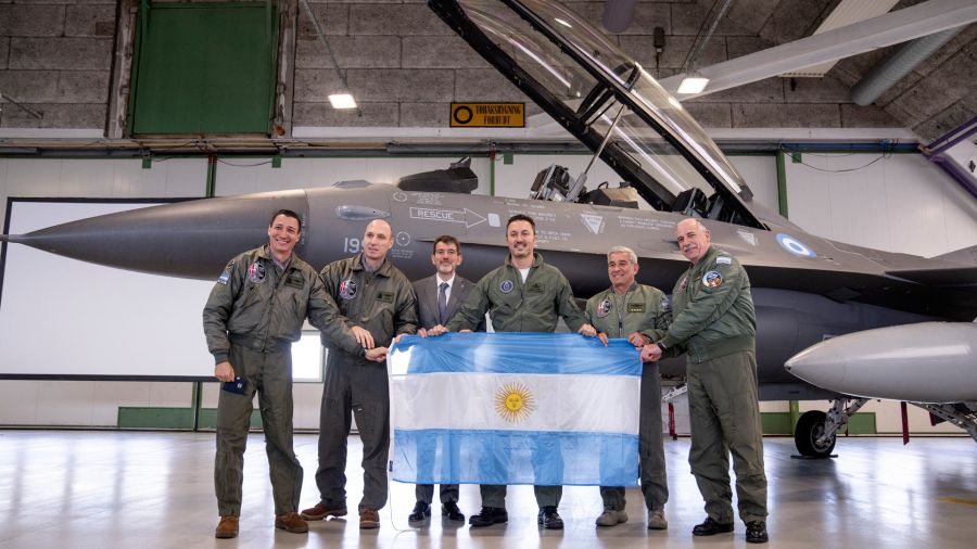 Photogallery Members of the Argentine delegation, including Defense Minister Luis Alfonso Petri, hold their national flag while posing in front of an F-16 fighter